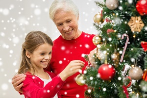 family, holidays, generation and people concept - smiling girl with grandmother decorating christmas tree at home